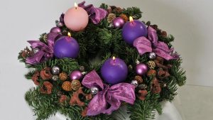 Klassisk adventskrans med fire lilla og rosa lys og bånd