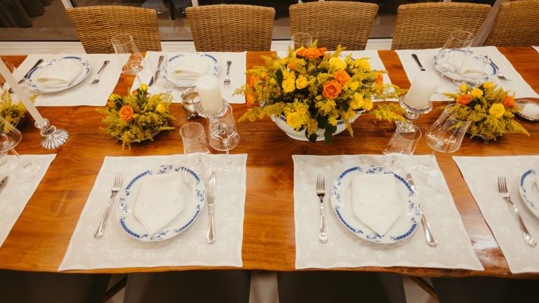 Langbord dækket op med tallerkener, bestik, glas og blomster