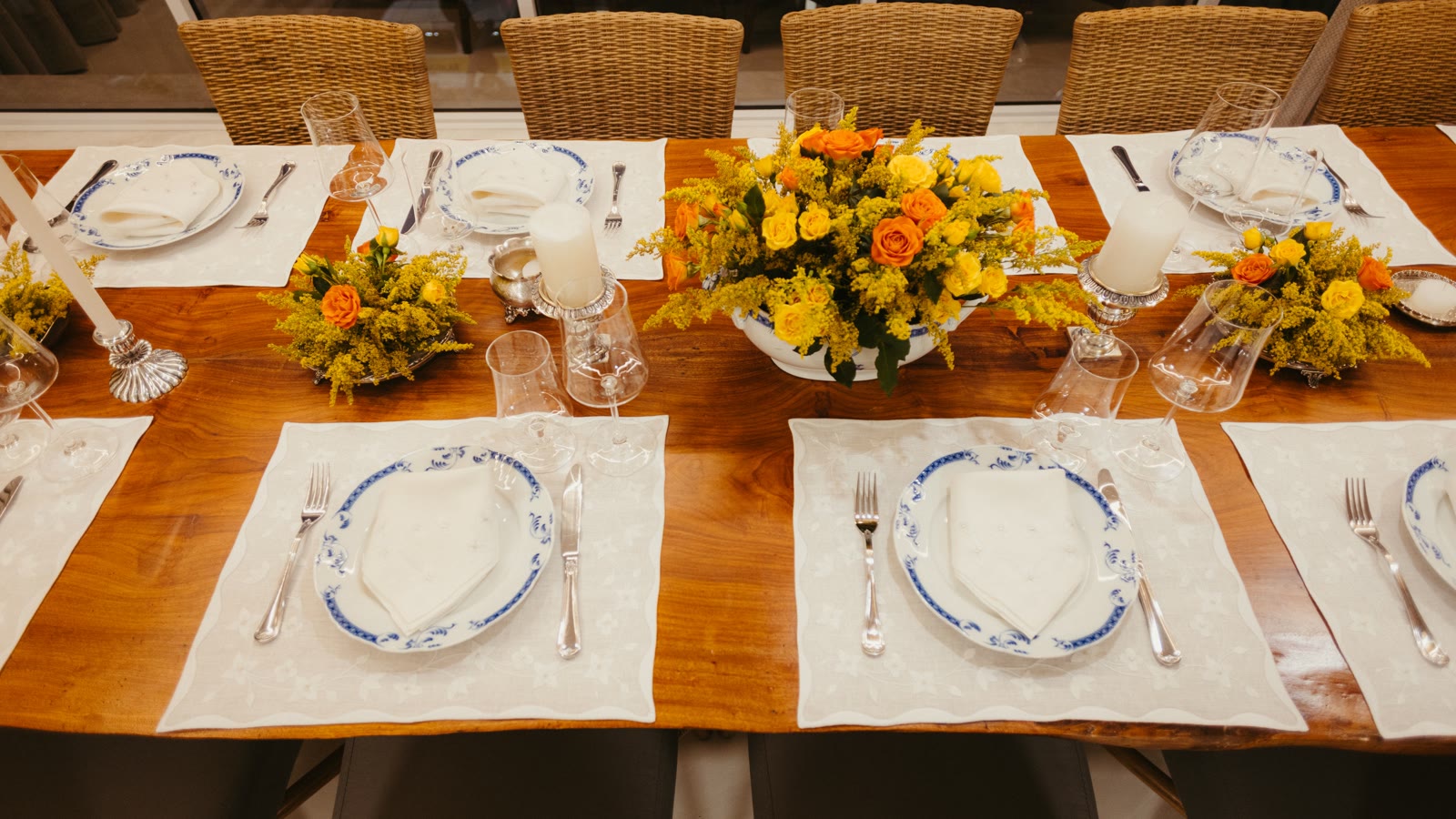 Langbord dækket op med tallerkener, bestik, glas og blomster