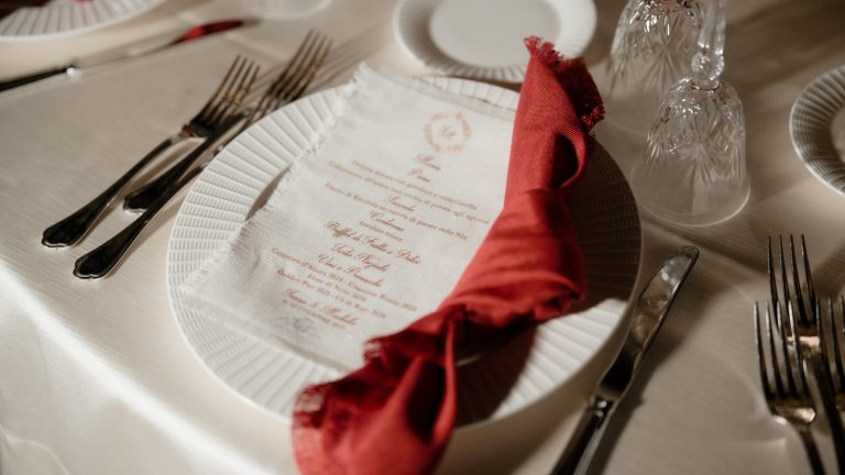 Klassisk rødt og hvidt julebord: kuvert med rød serviet, menukort, bestik og glas