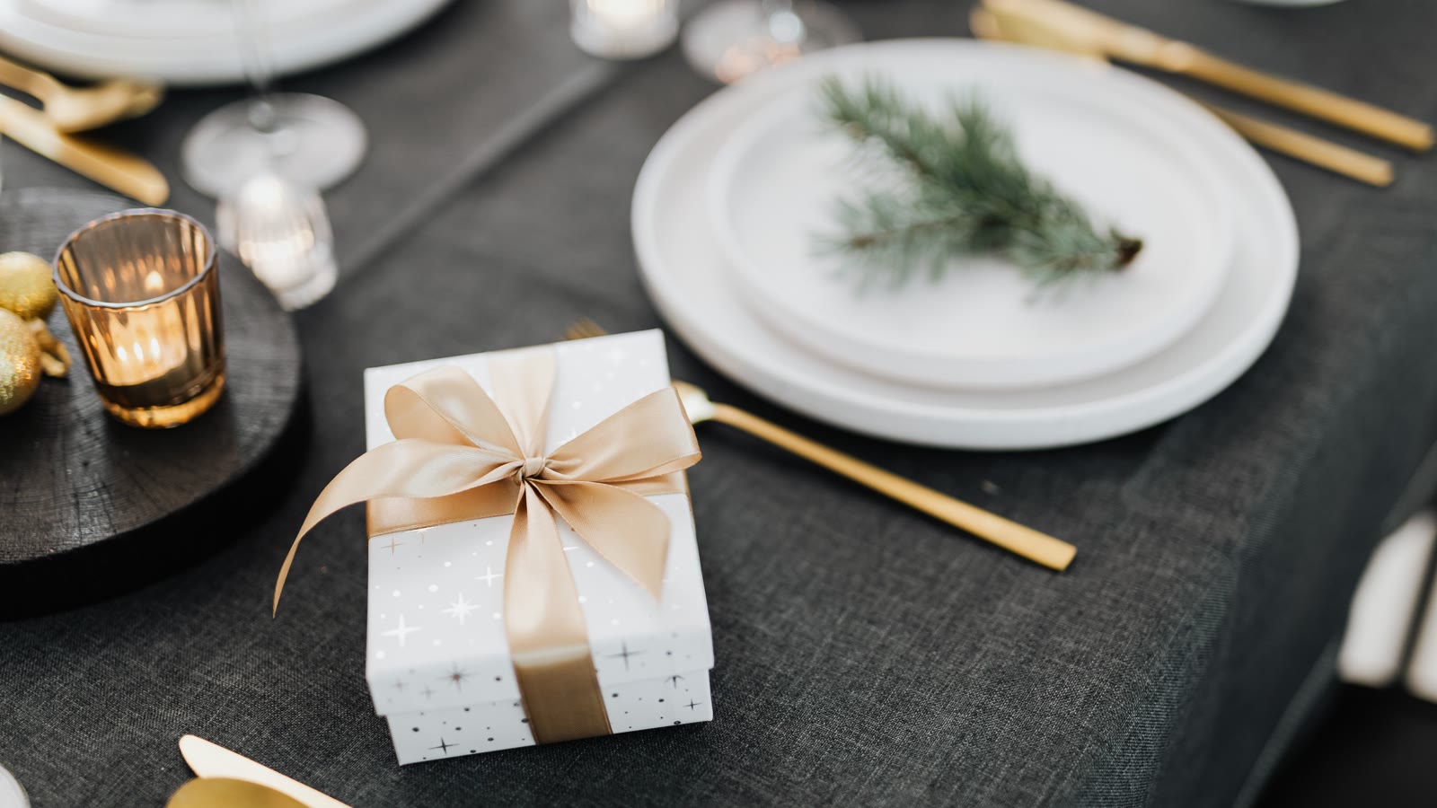 Minimalistisk julebord: mørk dug, hvide tallerkener og en enkelt grangren pr. kuvert