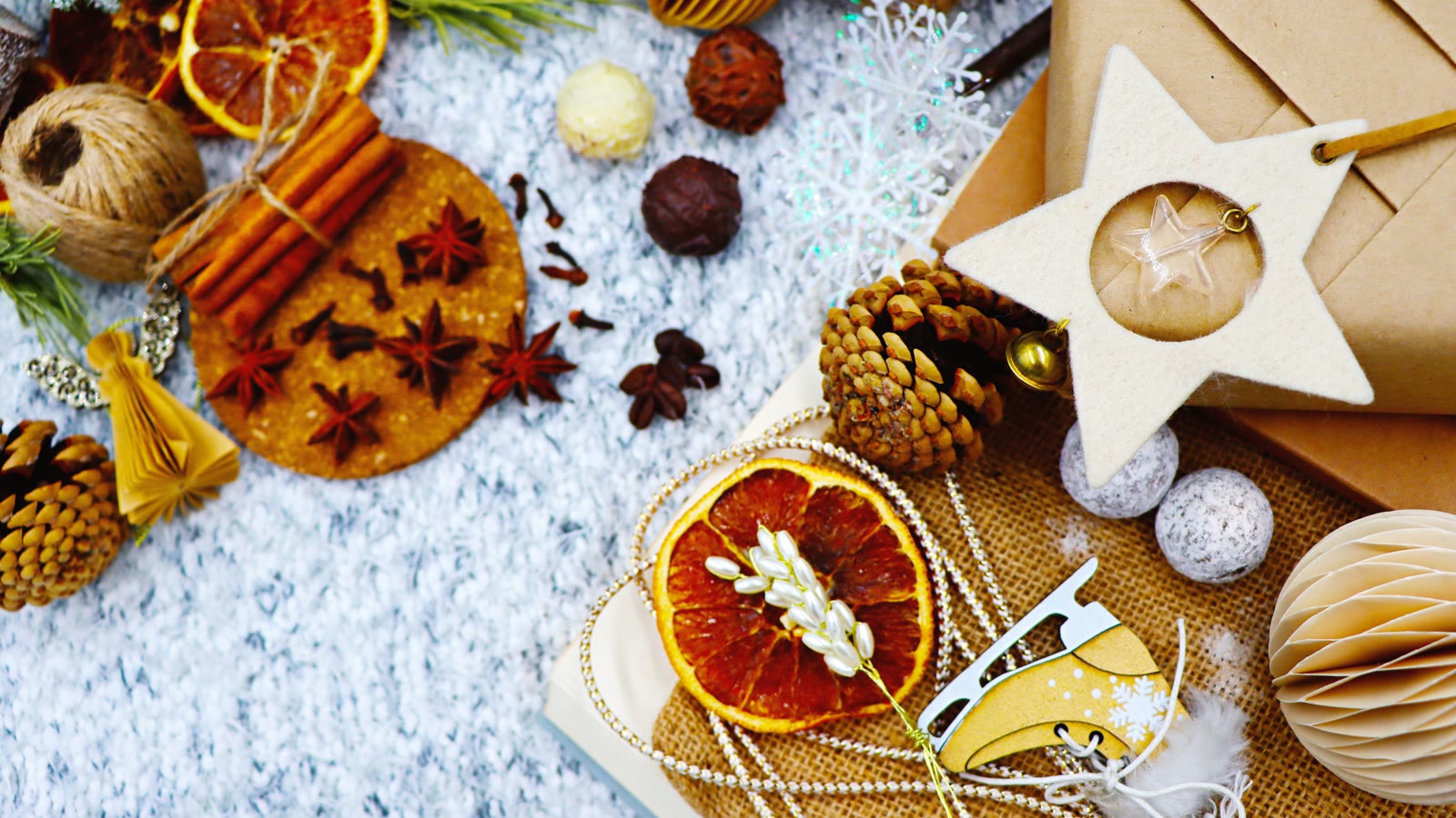 Naturlige julematerialer i flatlay: tørrede appelsinskiver, stjerneanis, kogler og papirstjerner
