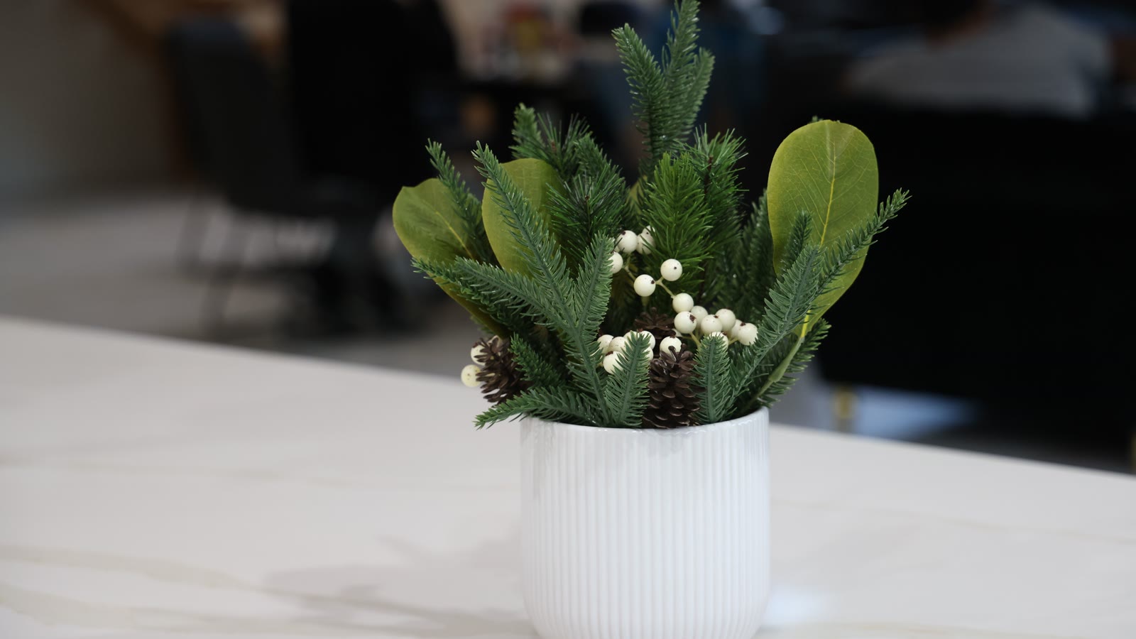 Miniature-juledekoration af grangrene og kogler i hvid vase