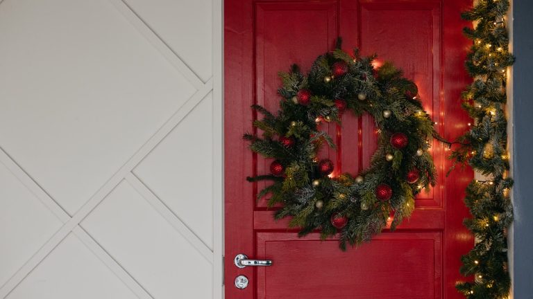 Grøn julekrans med kugler på en rød hoveddør