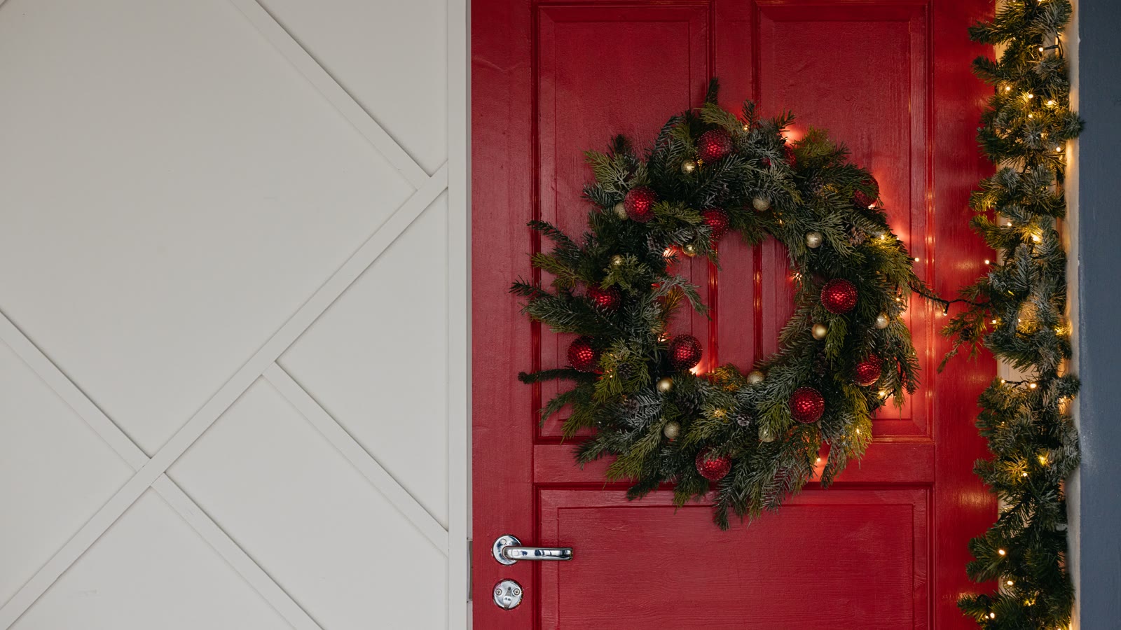 Grøn julekrans med kugler på en rød hoveddør