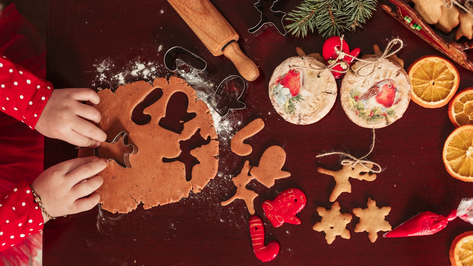 Barnehænder udstikker julefigurer i udrullet dej